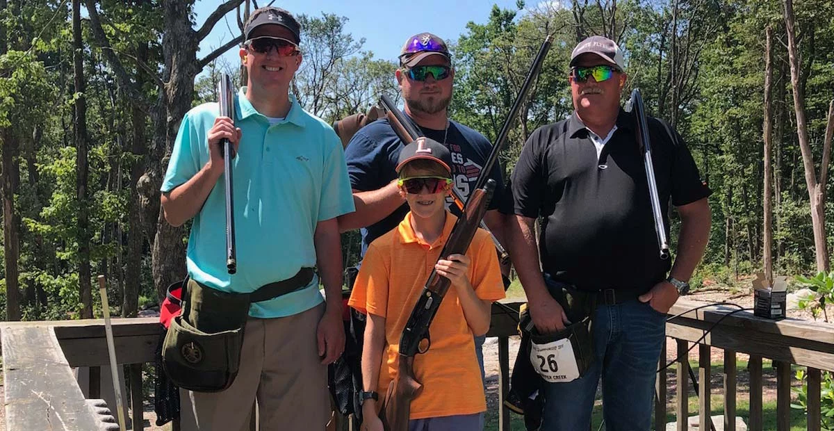 Group of men and a boy with rifling equipment.