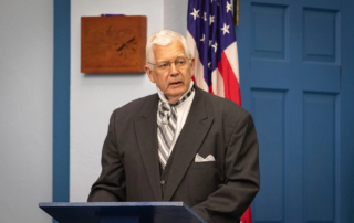 Man in suit and tie addressing a room.