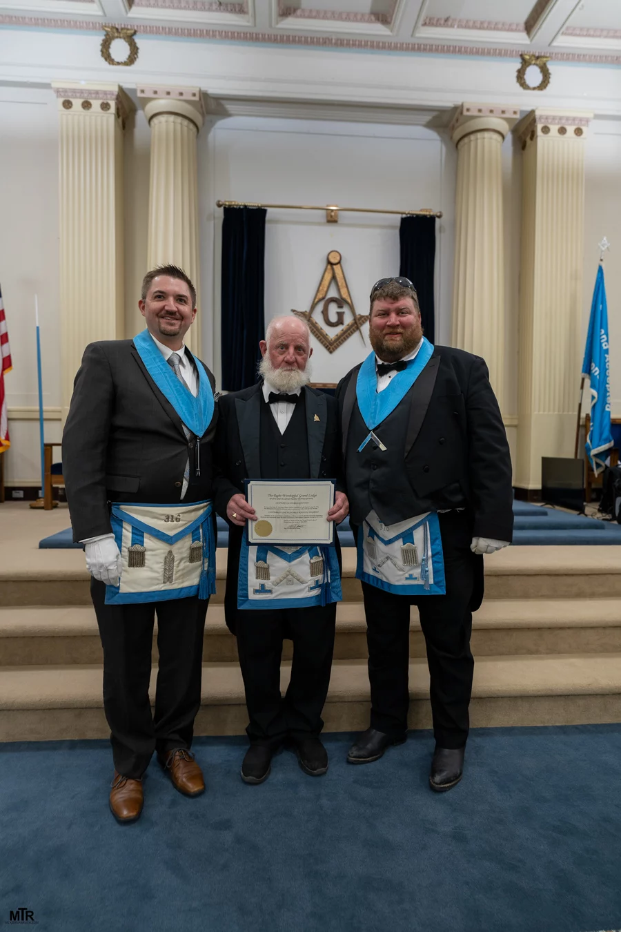 DSC06711 Masons standing in lodge, man in the center is holding up a certificate.
