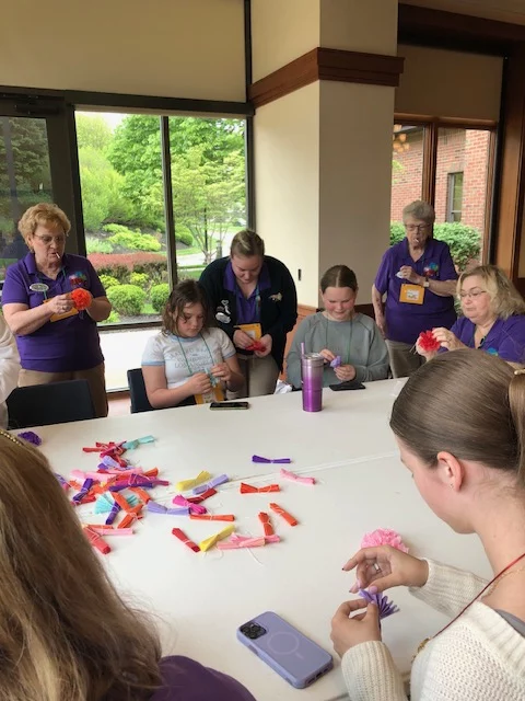 Rainbow Helen 2 Group of girls and adults making floral crafts together.