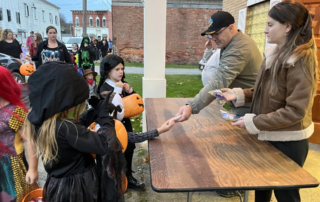 Volunteers handing out candy to children during Halloween.