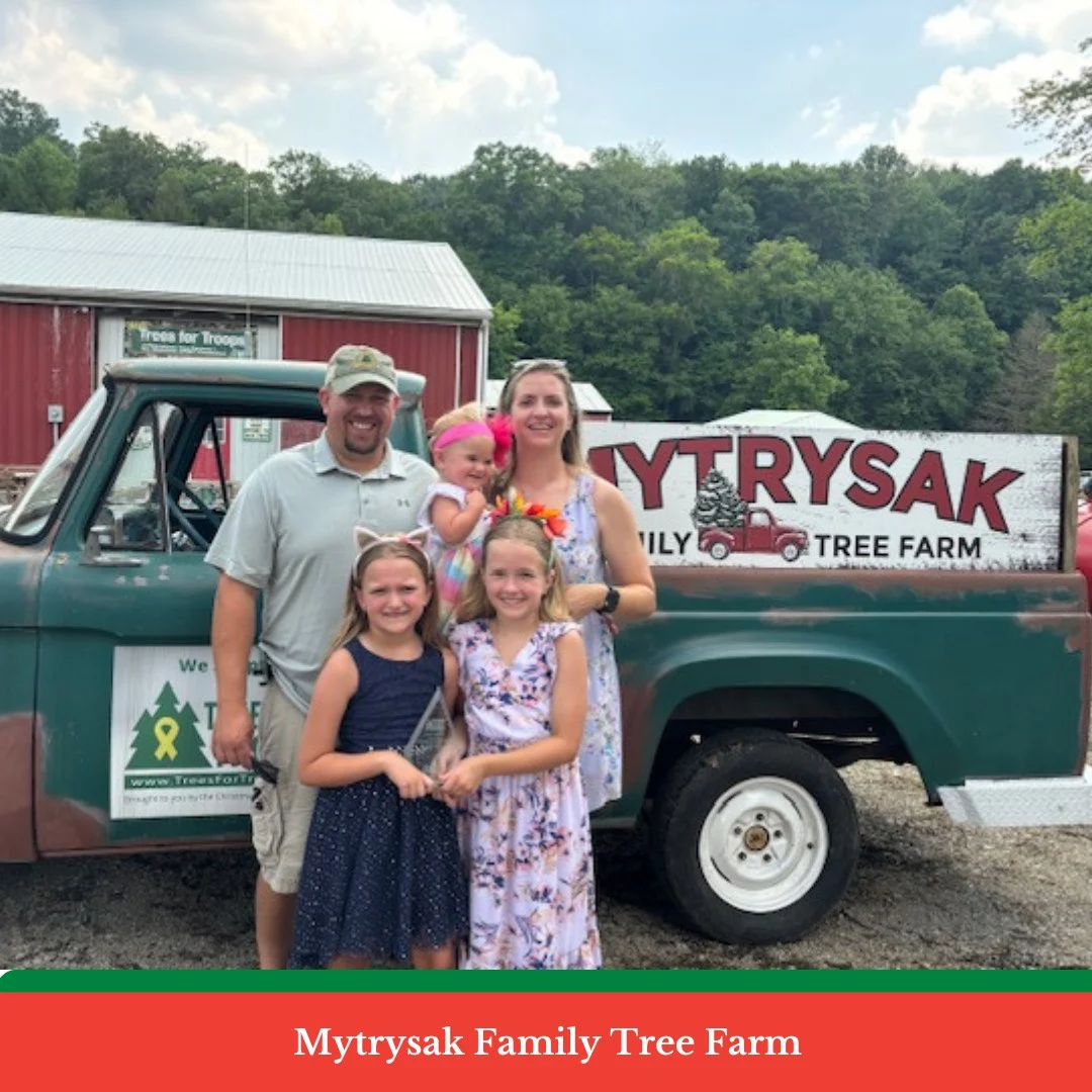 452169108_879683210863972_6662673011935450152_n Smiling family in front of farm sign and truck.