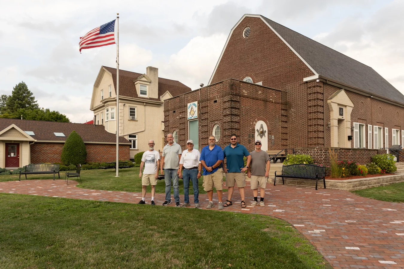 9I4A3901 Group of men standing outside of large brick lodge building.