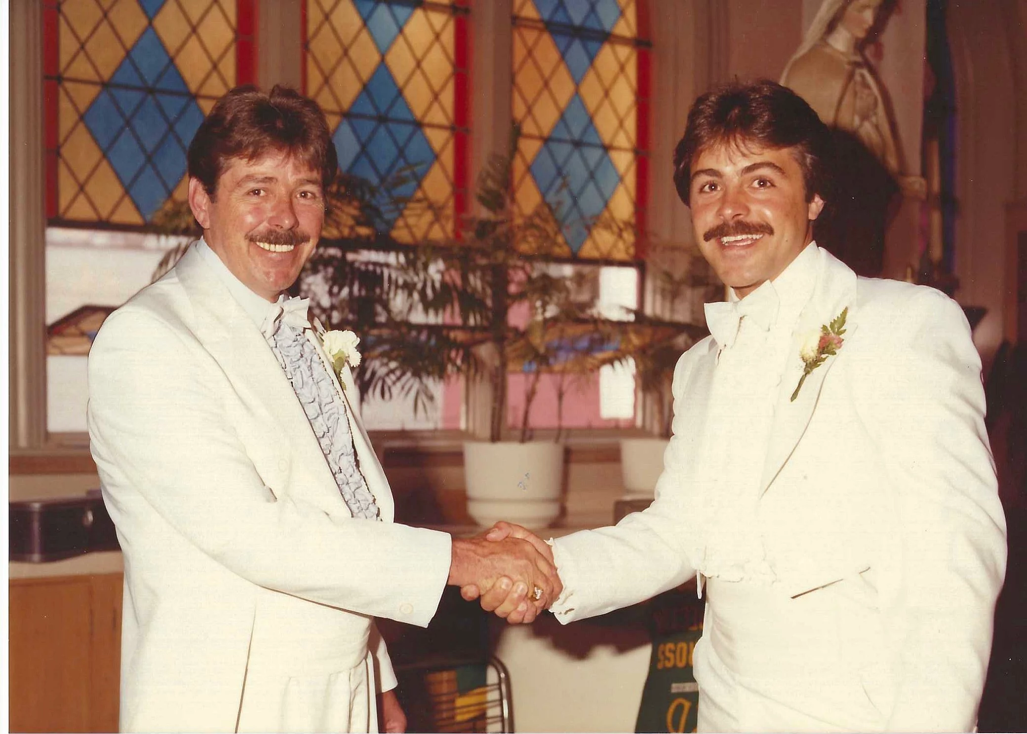 Aged photo of two smiling men om white shoes shaking hands.