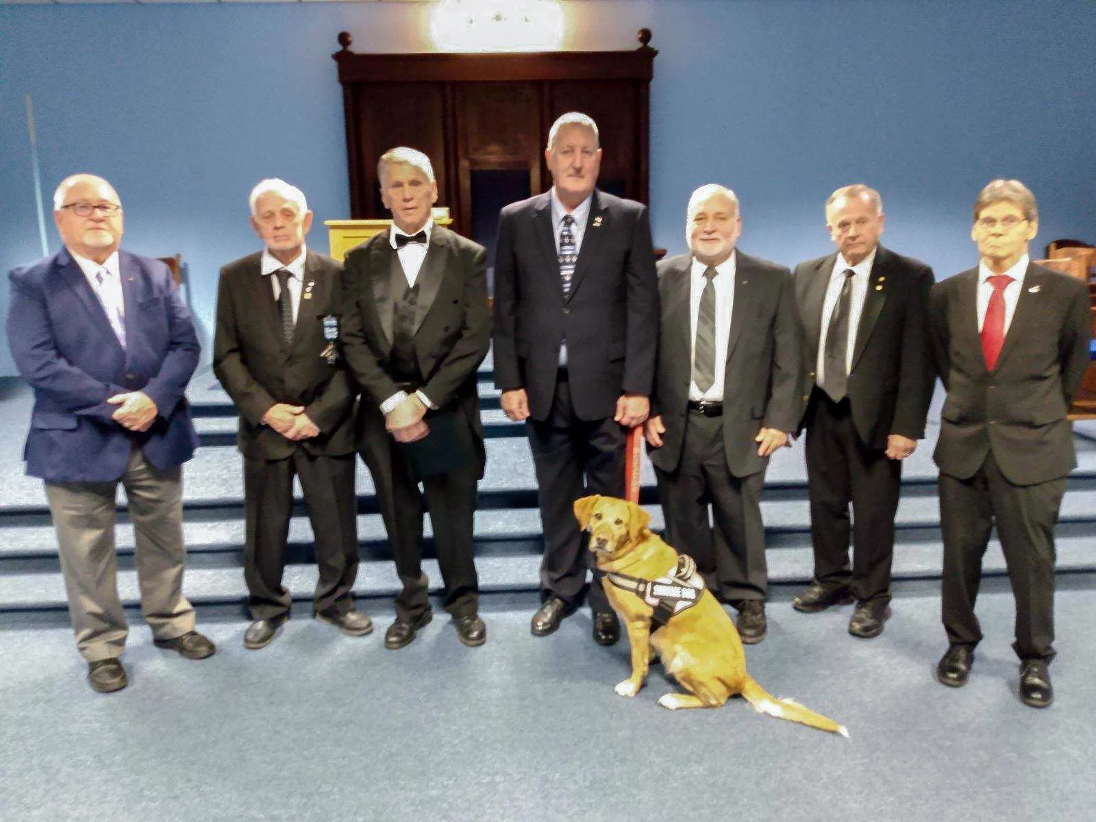 Lodge members, all veterans, all have something to do with veterans council. Lodge members, all veterans, standing in lodge with service dog.