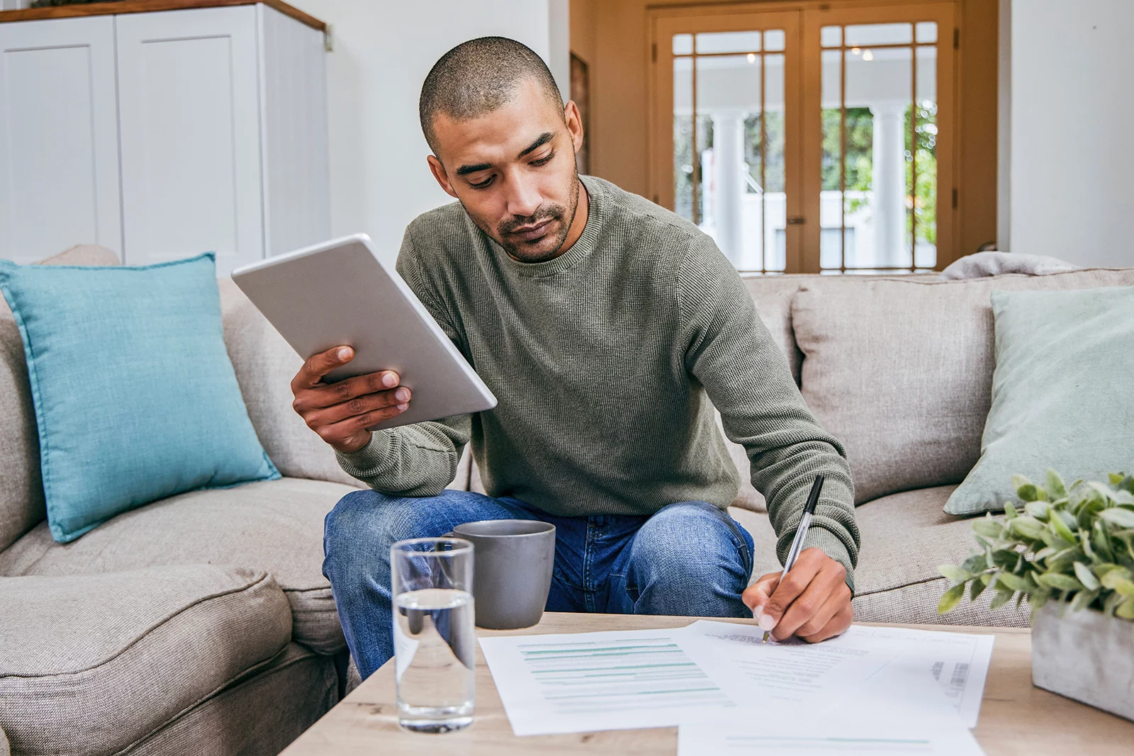 Man Sorting Through Paper Man holding tablet in one hand and writing on papers with the other.