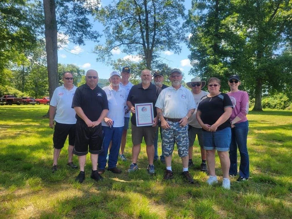 The plaque is from veterans council, thanking Elwood National Forge for use of facilities to have our picnic last several years. Group of people with plaque from veterans council.
