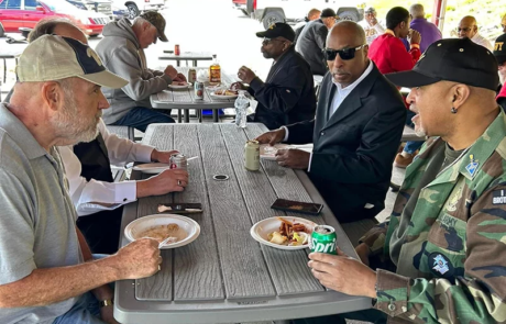Group of men eating together outdoors.