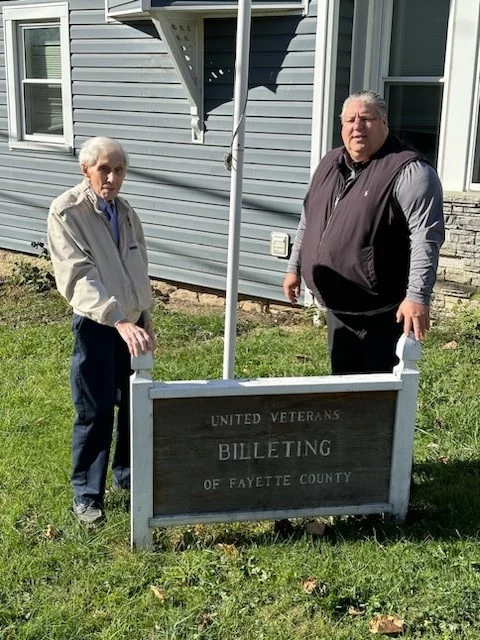 10 Two men standing behind "United Veterans Billeting of Fayette County" sign.