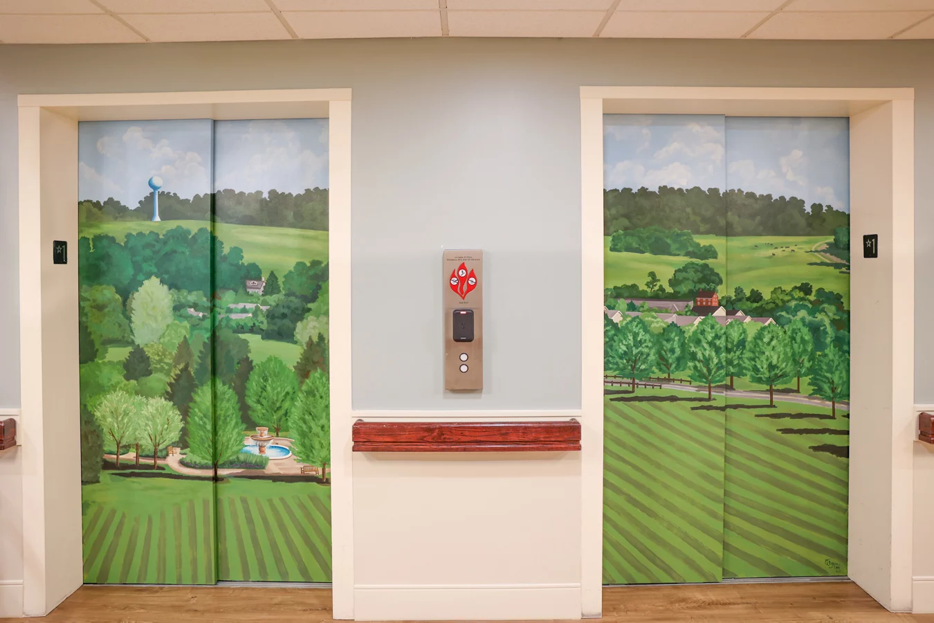 Wide shot of two beautifully painted sets of elevator doors showcasing a rural landscape.