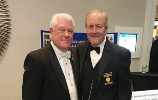 Two smiling men dressed in suits.