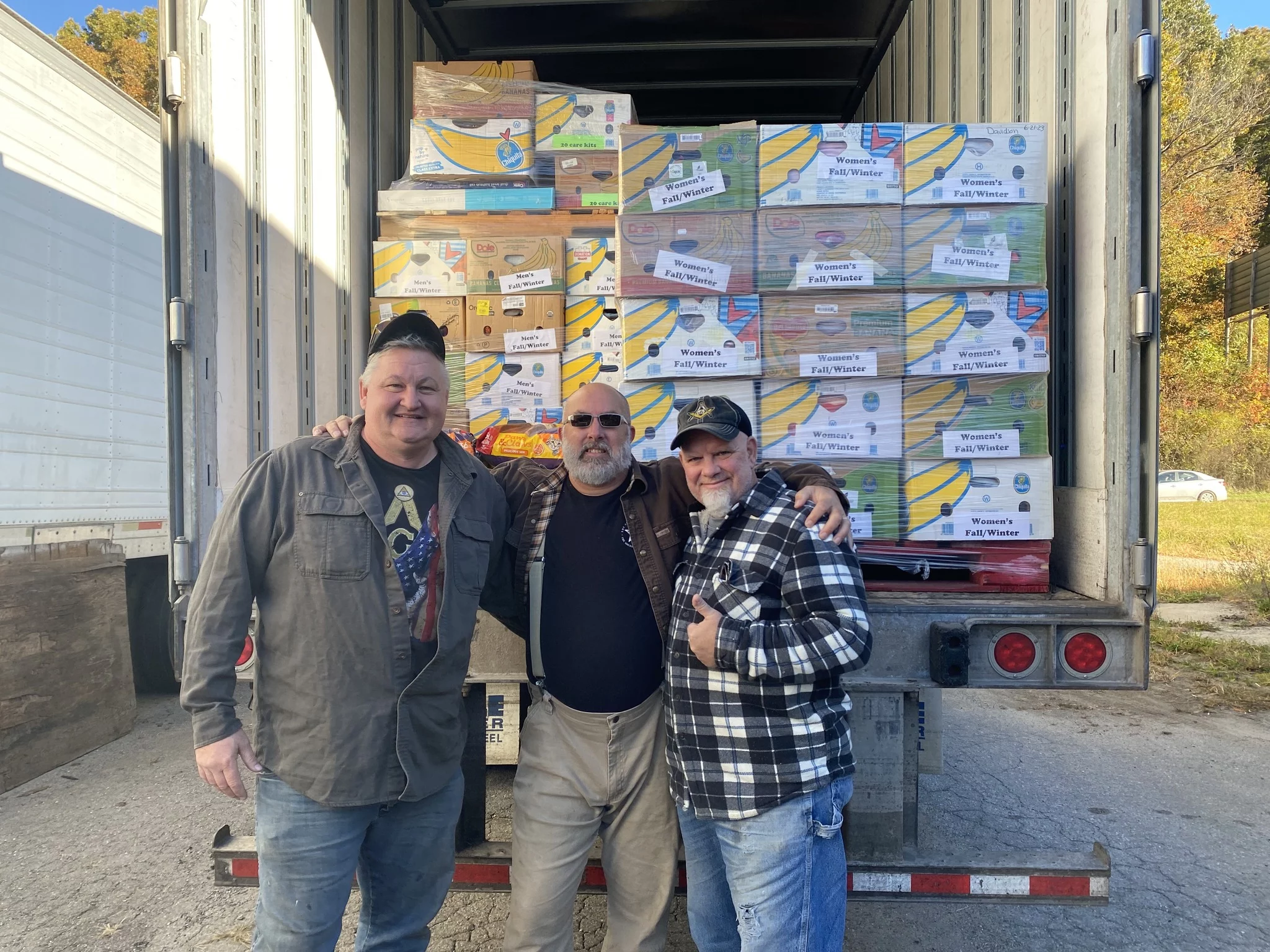 Group of smiling men with truck stacked with supplies.