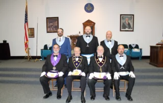 Group of smiling men posed together in lodge room in Masonic dress.