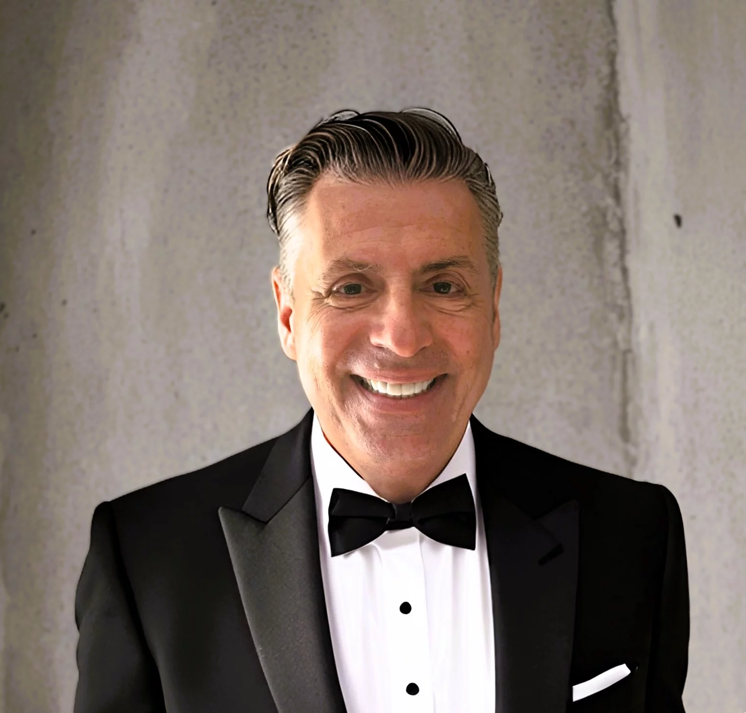 Smiling man in tuxedo with dark hair.