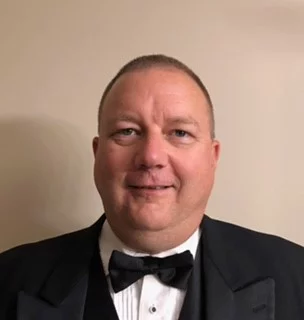 Man in tuxedo with short dark hair.