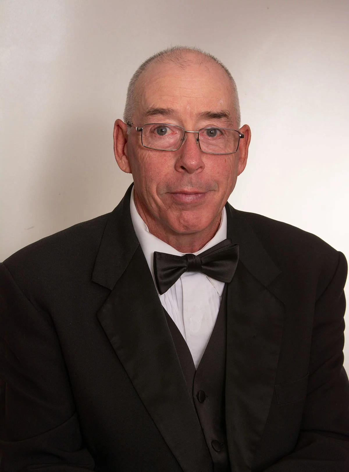 Man in tuxedo with glasses.