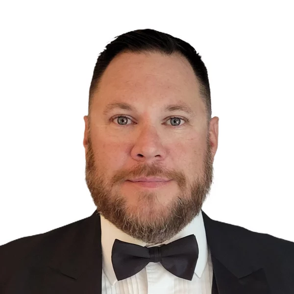 Man in tuxedo with short brown hair and beard.