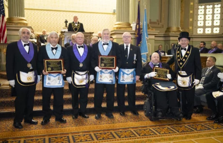 Group of men holding up awards while standing with Grand Master Larry Derr.