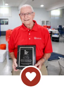 Smiling man holding plaque with heart icon.