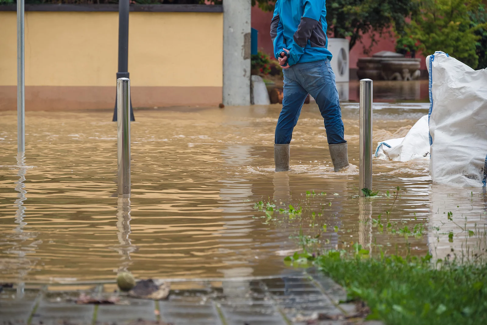 Person standing in deep flood waters with boots on.