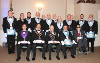 Group of smiling men dressed in Masonic regalia sitting and standing.
