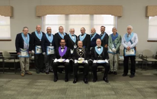 Group of men sitting and standing in Masonic dress.