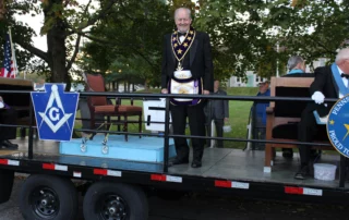 Grand Master Larry Derr smiling while standing on parade float.