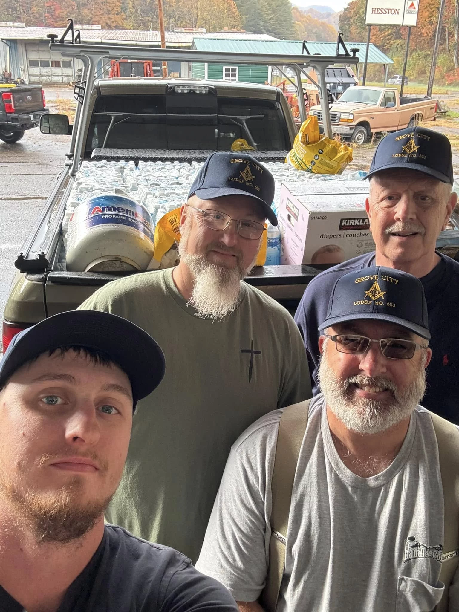 Group of four men wearing Masonic hats while standing in front of truck full of supplies.