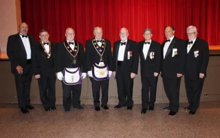Group of smiling men standing in front of stage.
