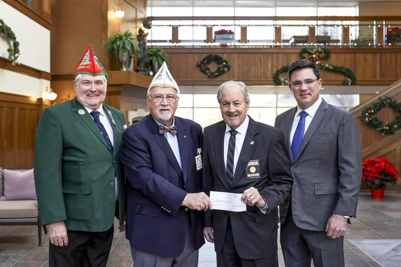 Smiling men from Tall Cedars holding check with R.W. Grand Master Larry Derr and Bill Kingsbury, CEO of Masonic Villages.