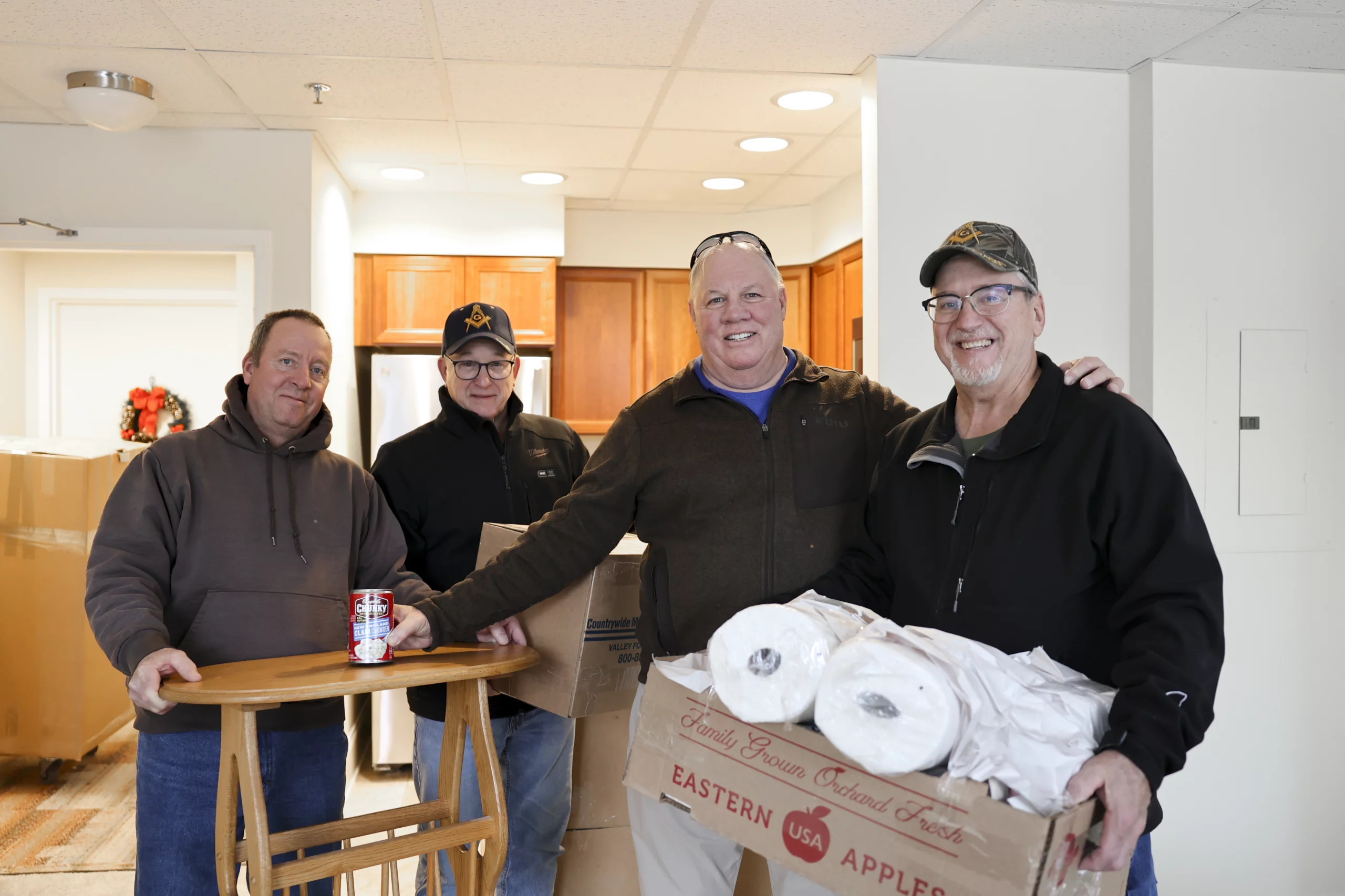 Smiling group of men carrying boxes and furniture.