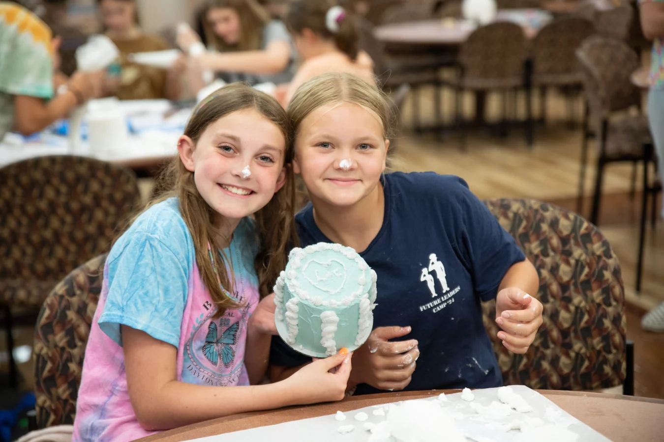 Smiling girls holding up blue cake.