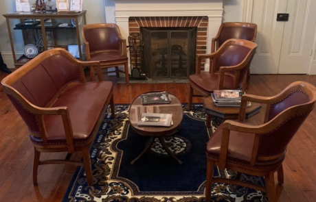 41-2 Museum room with framed photos on the wall with chairs and couch in center of room.