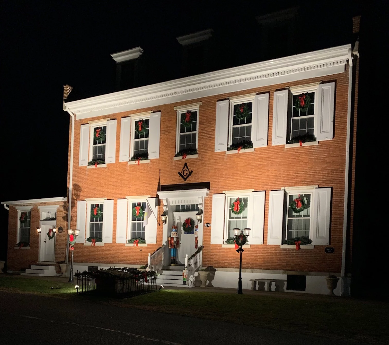 Red brick building decorated with wreathes and large nutcracker.