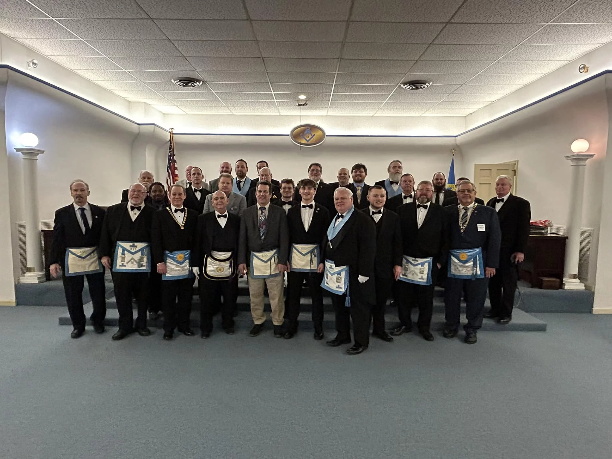 Group of smiling Masons standing together in lodge room.