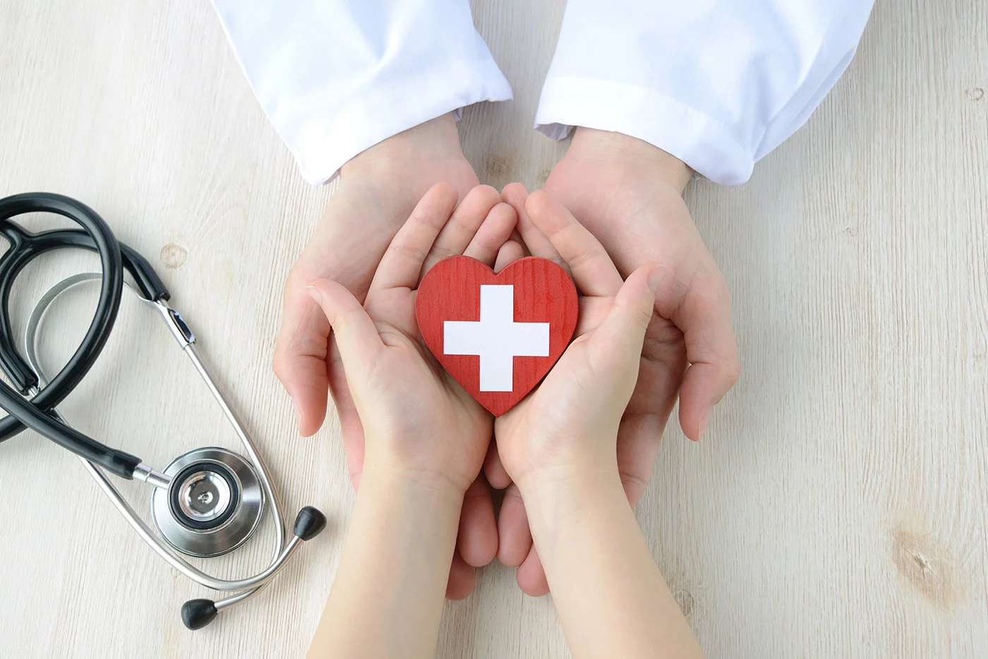 Two sets of hands holding heart.