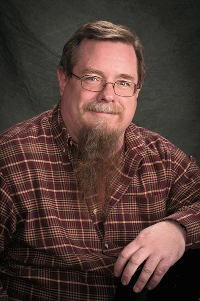 HickeyB-SPEM-3457-03-A Smiling man in front of black background.