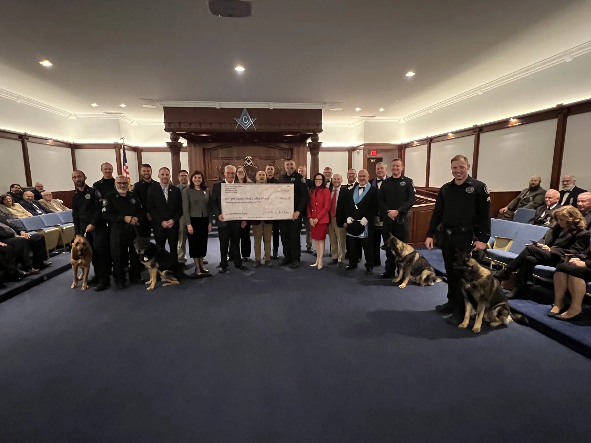 Smiling group standing with large check in lodge.