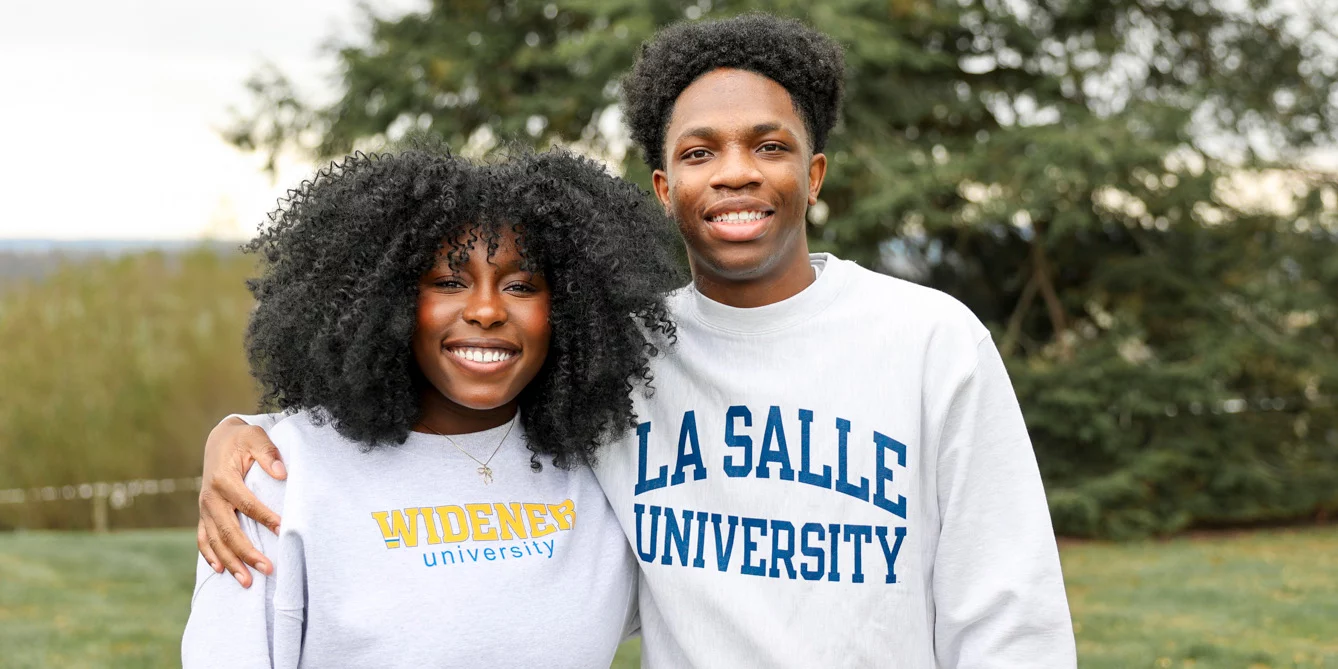Smiling teens wearing college sweatshirts.