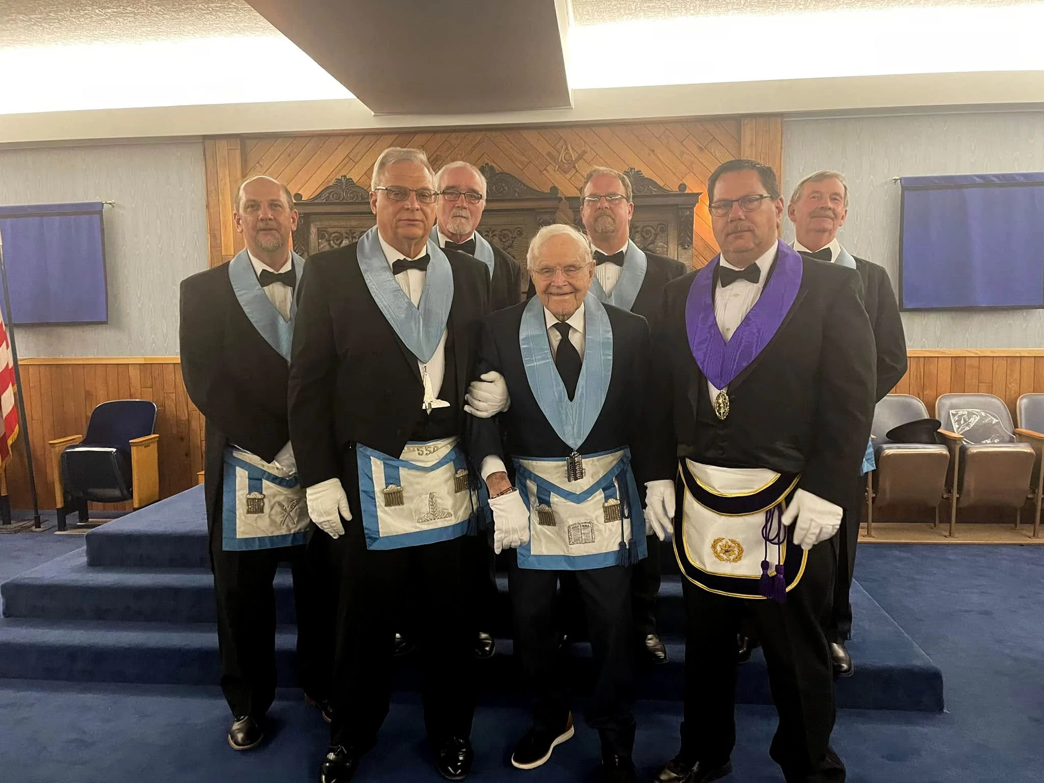 Group of men in masonic dressed standing together in lodge room.