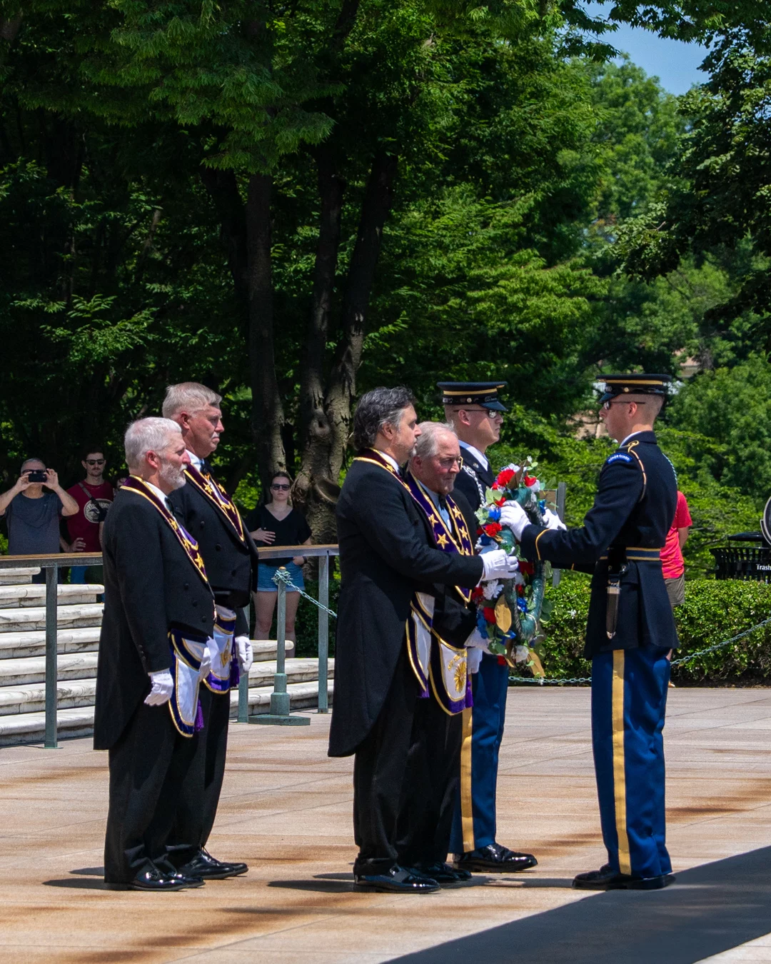 _7R50026 Grand Lodge officers handing red, white and blue wreath to man in military uniform.