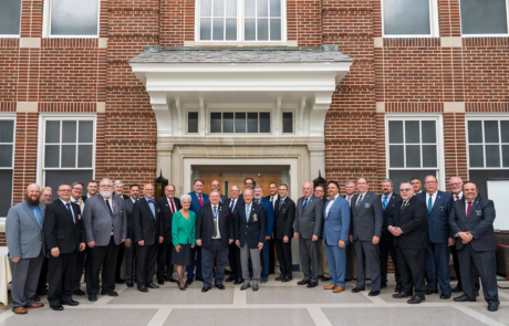 Large, formally dressed group standing in front of brick building.
