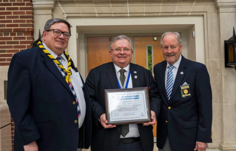 Smiling man holding certificate surrounded by David Berry and Grand Master Larry Derr.