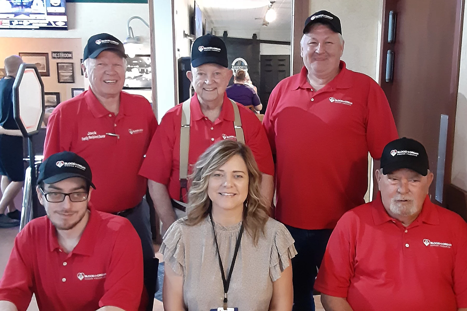 District 16 with Red Cross Group of smiling men wearing red Masonic Blood + Organ Donor Program shirts and hats and one woman.