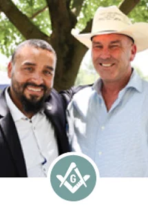 Two smiling men outdoors with Square and Compass icon.
