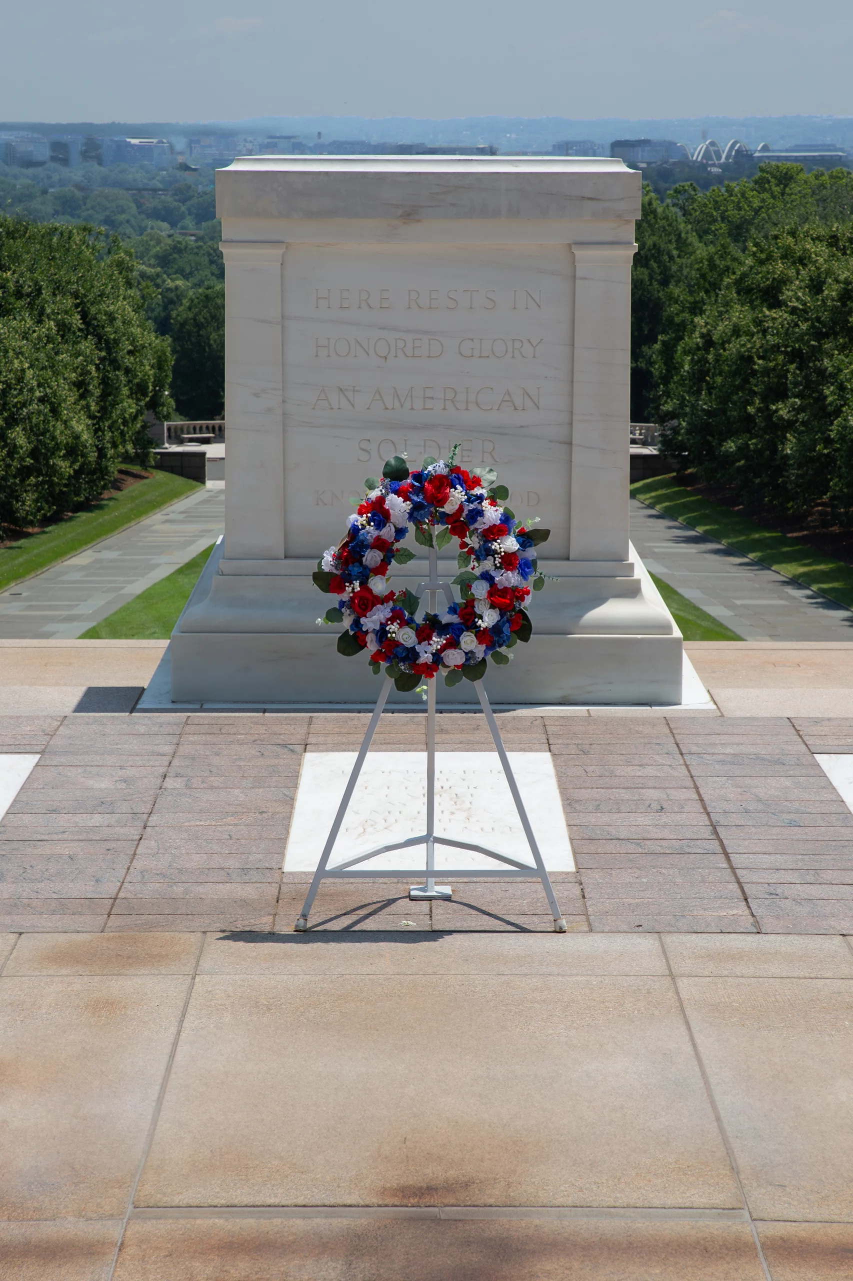 Red, white and blue wreath on stand in front of Tomb of the Unknown Soldier.