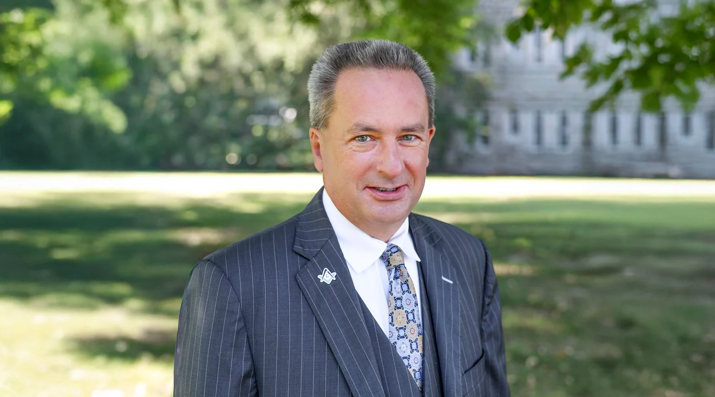 Smiling man in suit standing outdoors.