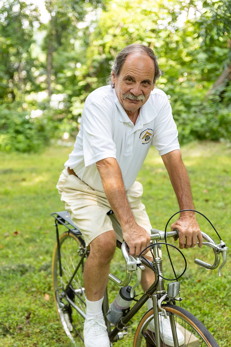9I4A5254 Smiling man on bicycle outdoors.