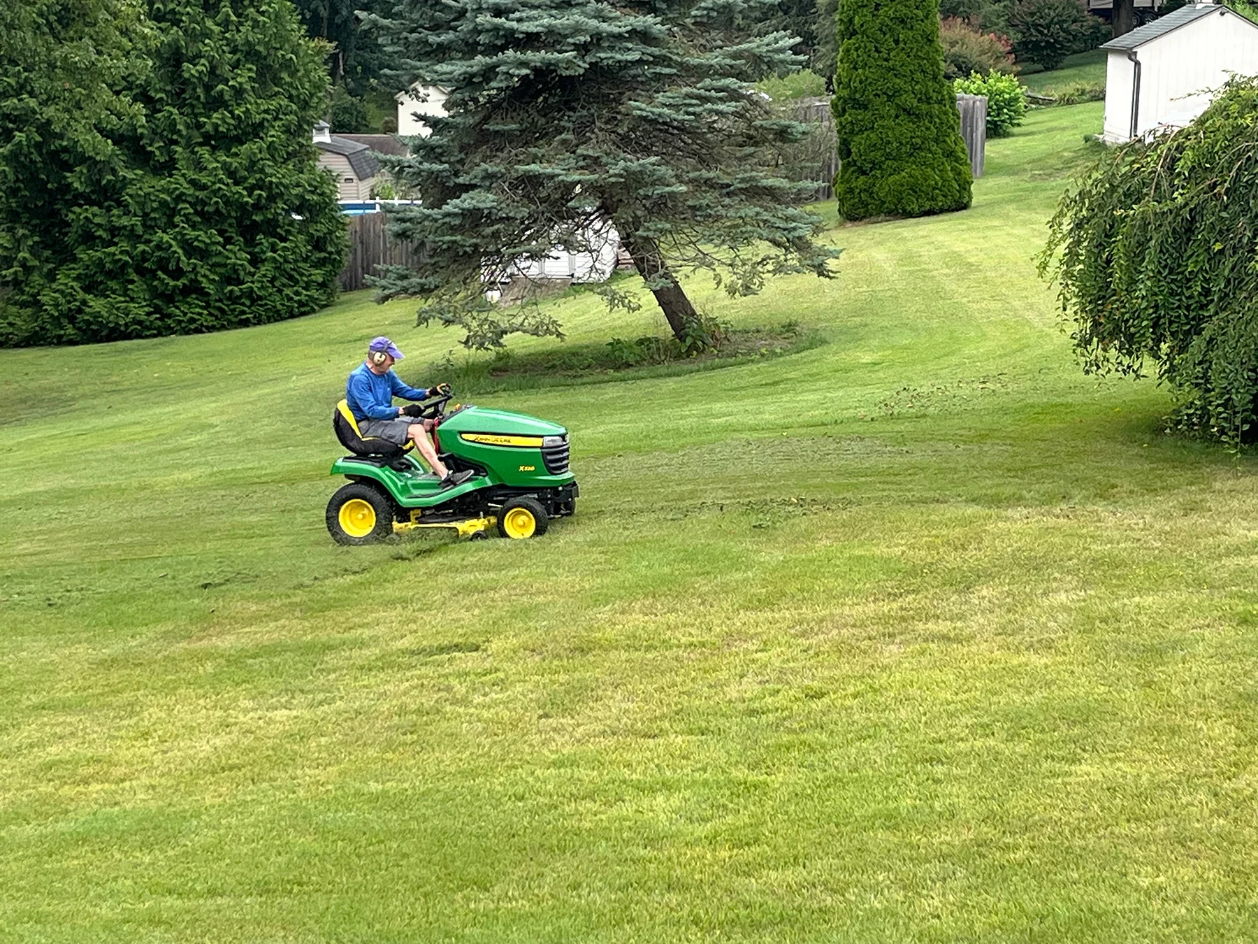 Man riding lawn mower outdoors.