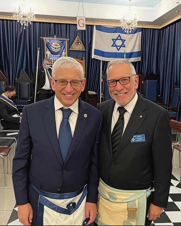 Israeli brother photo Two men in suits, ties and masonic aprons standing in lodge room.